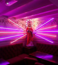 there is a statue in the middle of a room with purple lights and couches