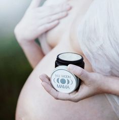 a pregnant woman holding a jar of cream