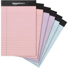 five pink and blue lined notebooks with amazon basics written on the top one in black