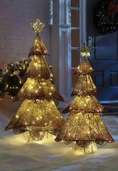 two lighted christmas trees sitting in the snow