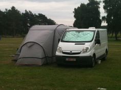 a van with a tent attached to it parked in the grass