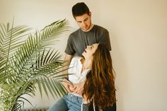 a man standing next to a woman near a plant