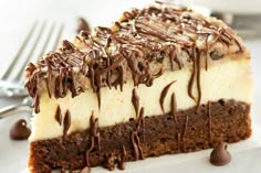 a piece of cheesecake with chocolate drizzled on top, sitting next to a fork