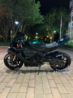 a black motorcycle parked on top of a brick road next to a street light at night