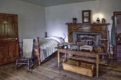 an old fashioned bedroom with a fireplace and bed in the corner, next to a wooden dresser