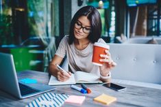 a woman sitting at a table with a notebook and coffee