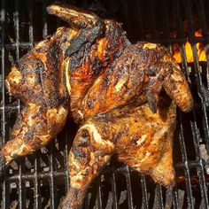 a chicken is cooking on the grill with it's legs still attached to it