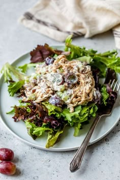 a white plate topped with lettuce and salad next to two silver forkes