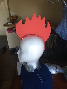 a white mannequin head wearing a red crown on top of it's head