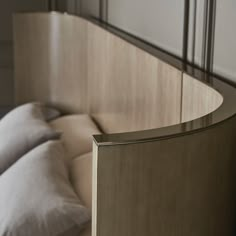 a bed with white pillows and a curved headboard