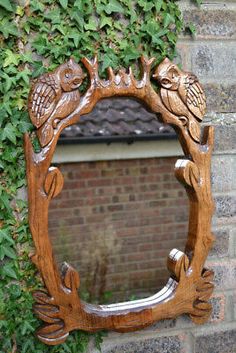 an ornate wooden mirror hanging on the side of a brick wall with ivy growing around it