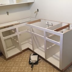 an unfinished kitchen with white cabinets and tools on the floor