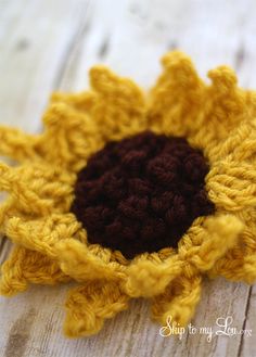 a crocheted sunflower sitting on top of a wooden table