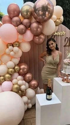 a woman standing next to a cake and balloons