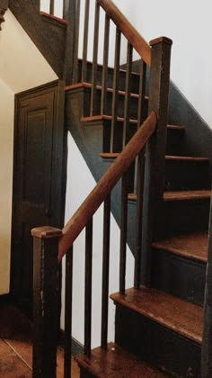 a wooden stair case next to a white wall