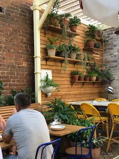 people sitting at tables with plants on the wall