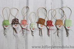 five small wooden ornaments hanging from strings on a white wood wall, each decorated with different patterns and colors