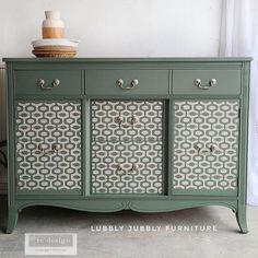 an old dresser painted in green and white with decorative designs on the doors, drawers and handles