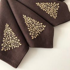 three brown napkins with gold designs on them