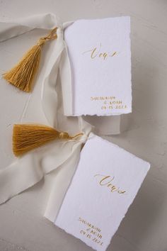 two white cards with gold lettering and tassels