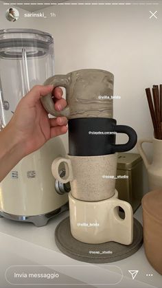 a person holding a coffee cup in front of a blender