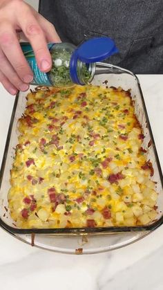 a person is adding seasoning to a casserole dish