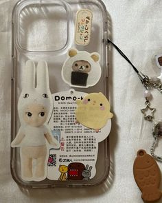 a cell phone case with some stickers attached to it's side and an animal keychain next to it