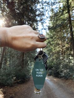 a person holding onto a keychain that says on the road again