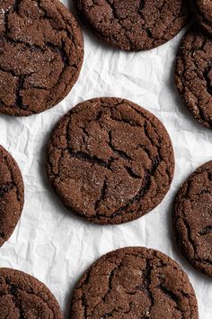 several chocolate cookies are arranged on a piece of paper