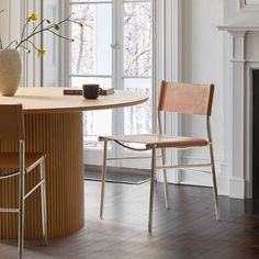 a table with two chairs and a vase on top of it next to a fireplace