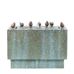 four birds are perched on top of a concrete block that is painted blue and has gold speckles