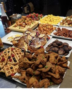 a table topped with lots of different types of food next to bottles of beer and plates of waffles