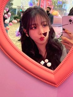 a woman taking a selfie in front of a heart shaped mirror with candy on it