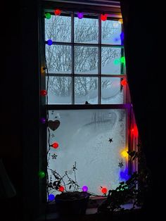 an open window with christmas lights on the outside, and trees in the back ground