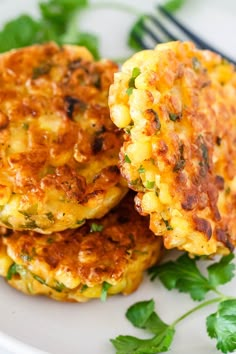 two crab cakes on a white plate with parsley around them and a fork in the background