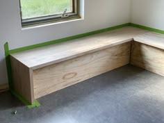 a wooden bench sitting next to a window in a room with green tape on the floor