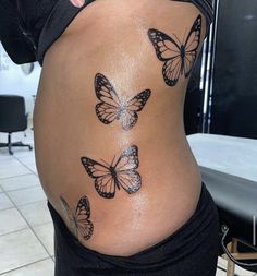 a woman's stomach with butterflies painted on the side and behind her belly, in front of a tiled floor