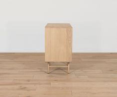 a wooden cabinet sitting on top of a hard wood floor next to a white wall