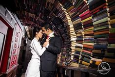 a man and woman standing next to each other in front of a book store filled with books