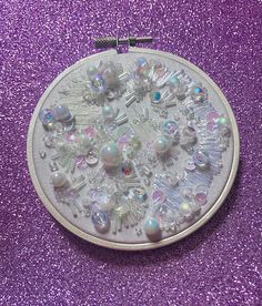 a close up of a small circular object on a purple glittered surface with beads