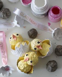 some little chicks are sitting in an egg carton with paint and glue on it