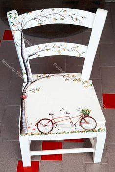 a white chair with a tree painted on the back and seat, sitting in front of a tile floor