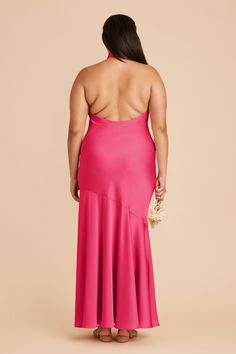 a woman in a bright pink dress with her back turned to the camera, looking down