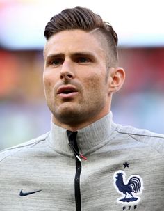 a close up of a soccer player wearing a gray jacket and black tie with a rooster on it