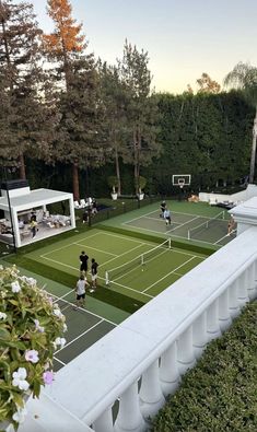 an aerial view of a tennis court with people playing on the court and trees in the background