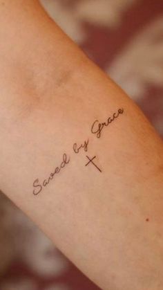 a woman's arm with the words saved by grace tattooed on her left arm