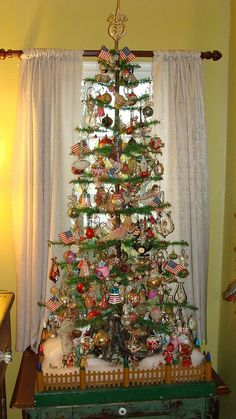 a christmas tree with ornaments on it in front of a window