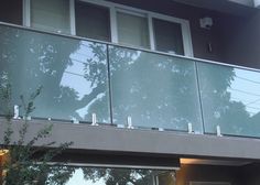 a balcony with glass railing and trees in the background