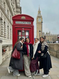 three women standing in front of a red phone booth with big ben in the background