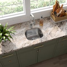 a kitchen sink sitting under a window next to a counter top with utensils